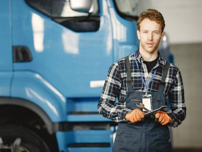 Young truck mechanic in front of a lorry