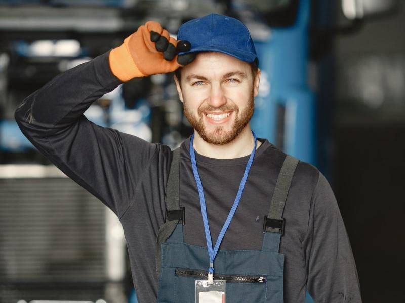 Smiling young mechanic in work overalls