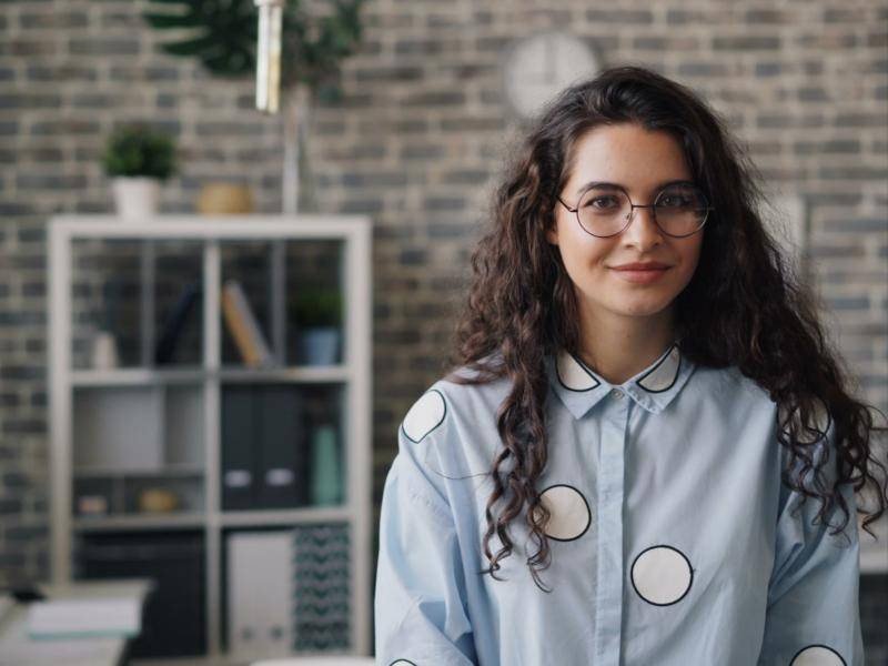 Young woman with glasses smiling in an office