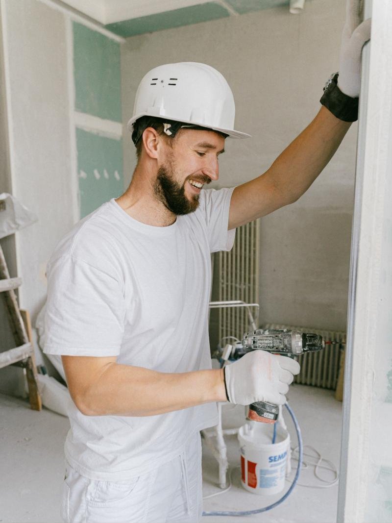 Smiling young craftsman in a white hard hat at work